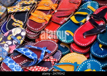 Bunte handgemachte Chappalls (Sandalen), die auf einem indischen Markt verkauft werden, handgefertigte Lederschuhe, traditionelle Schuhe. Stockfoto