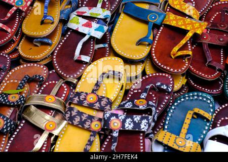 Bunte handgemachte Chappalls (Sandalen), die auf einem indischen Markt verkauft werden, handgefertigte Lederschuhe, traditionelle Schuhe. Stockfoto