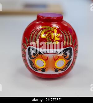 Nahaufnahme von Daruma oder einer rot gestrichenen Glückspuppe auf einem weißen Tisch Stockfoto