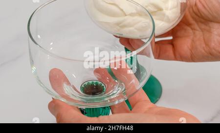Frau Hände dienen Dessert in Glas Dessertbecher. Nahaufnahme, Marmorhintergrund, Kopierbereich Stockfoto