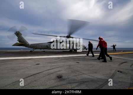 211121-N-HS181-1066 PHILIPPINISCHES MEER (NOV 21, 2021) Seeleute nähern sich während 70 der jährlichen Übung (ANNUALEX), November 21, einem MH-60s Sea Hawk, der den „Schwarzen Knights“ des Hubschrauber-Seekampfgeschwaders HSC 4 zugewiesen wurde. ANNUALEX 2021 ist eine multilaterale Übung, die von Elementen der Royal Australian, Royal Canadian, German, Japan Maritime Self-Defense Force und US-Marine durchgeführt wird, um die Unfähigkeit der Marine und ein gemeinsames Bekenntnis zu einem freien, offenen und inklusiven Indo-Pacific zu demonstrieren. (USA Navy Foto von Mass Communication Specialist 2N Stockfoto