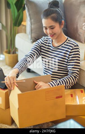 Porträt einer Gründerin eines kleinen Unternehmens, die ein Paket verpackt, um die Lieferung an ihren Kunden zu senden. KMU-Geschäftskonzept. Stockfoto