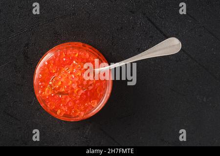 Blick von oben auf ein offenes Glas mit rotem Kaviar und einem Löffel darin Stockfoto