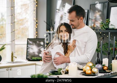 Junge liebevolle Paar gute Zeit am Weihnachtsmorgen in der Küche Stockfoto