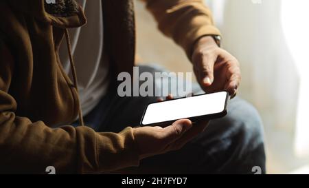 Ein Mann chattet auf Smartphone-Anwendung, mit Handy. Smartphone leeren Bildschirm Mockup. Zugeschnittenes Bild. Stockfoto