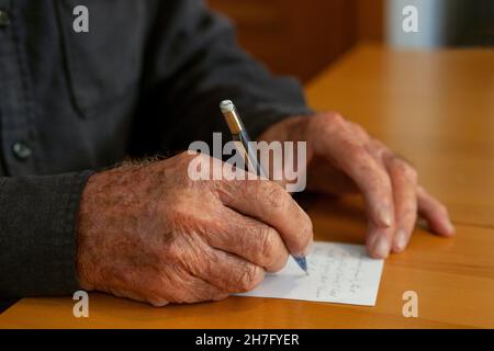 Eine Nahaufnahme der Hände eines älteren Mannes, der eine Notiz SCHRIEB MR - Model veröffentlicht Stockfoto