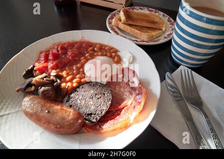 Günstige Cafe gebraten englisches Frühstück Ei Speck Wurst Black Pudding Bohnen Tomaten und Pilze mit Toast und Tee New Brighton The Wirral merseysi Stockfoto