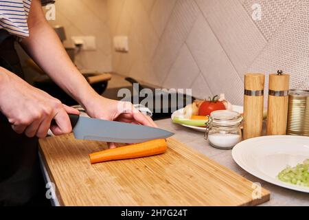 Frau mit Messer schneidet frische Karottenscheiben zum Kochen Stockfoto