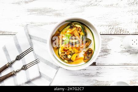 Zucchini mit Pilzen und Karotten. Gebackenes Gemüse mit essbaren Pilzen. Gesundes und leckeres vegetarisches Essen. Bio-Lebensmittel auf einem rustikalen Hintergrund Stockfoto