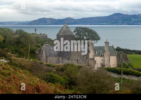 Penmon Priorat auf der Isle of Anglesey mit dem Festland im Hintergrund, Nordwales, Großbritannien Stockfoto