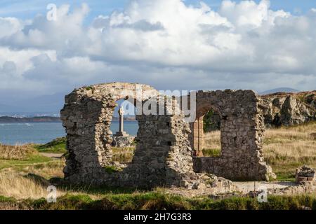 Das keltische Kreuz wurde durch die Ruinen der St. Dwynwen-Kirche auf der Insel Llanddwyn, Anglesey, Wales, gesichtet Stockfoto