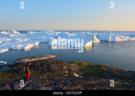 DÄNEMARK. GRÖNLAND. WESTKÜSTE. TOURISTEN VOR DEM FJORD VOLLER EISBERGE, DIE VOM GLACIAR VON ILULISSAT KOMMEN. Stockfoto