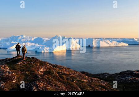 DÄNEMARK. GRÖNLAND. WESTKÜSTE. TOURISTEN VOR DEM FJORD VOLLER EISBERGE, DIE VOM GLACIAR VON ILULISSAT KOMMEN. Stockfoto