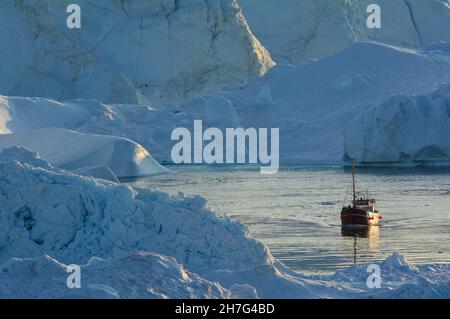 DÄNEMARK. GRÖNLAND. WESTKÜSTE. BOOT MIT TOURISTEN IM FJORD VOLLER EISBERGE, DIE VOM GLACIAR VON ILULISSAT KOMMEN. Stockfoto