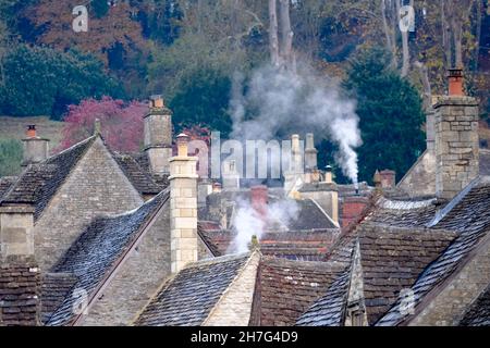 Castle Combe, Wiltshire, Großbritannien. 23rd. November 2021. Ein frostiger Herbstmorgen im historischen Dorf Castle Combe. Es werden Feuer angezündet, um die Hütten zu erwärmen, trotzdem bewegt die kalte Luft den Rauch nicht. In einem Tal im südlichen Teil der Cotswolds gelegen, fangen die Hütten dieses typisch englischen Dorfes den Frost ein. Kredit: JMF Nachrichten/Alamy Live Nachrichten Stockfoto