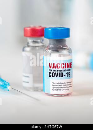 Zwei Flaschen Covid 19 Coronavirus-Impfstoff und eine Spritze auf dem weißen Tisch. Die medizinische Konzeption der Bekämpfung der Covid-19-Pandemie. Vertikale imag Stockfoto