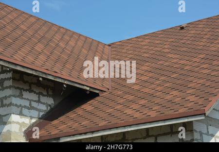 Brauner Asphalt verspachtelt Dach Tal undicht Problembereich mit einer Belüftungskappe. Eine Nahaufnahme von Asphaltschindeln, die auf einem Dachtal mit Wasser installiert sind Stockfoto