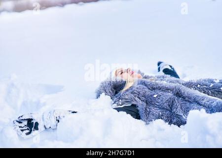 Junge nette Frau, die auf dem Schnee liegt Stockfoto