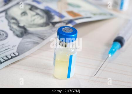 Nahaufnahme einer Spritze, einer Glasampulle mit flüssigen und Dollarnoten. Geschäft über Impfkonzept Stockfoto