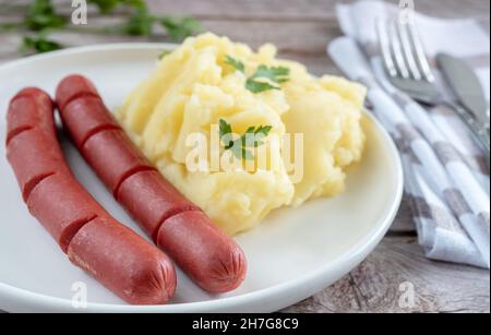 Hausgemachte Kartoffelpüree mit Würstchen zum Mittagessen auf einem weißen Teller. Stockfoto