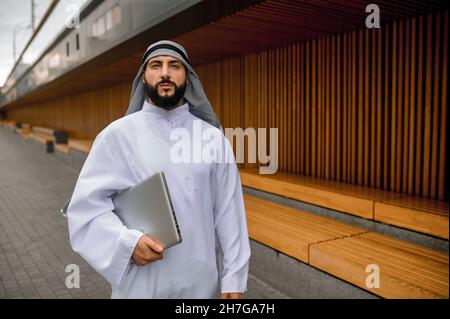 Junger arabischer Geschäftsmann mit einem Laptop in den Händen Stockfoto