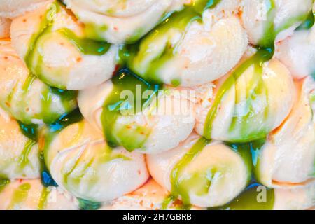 Leckeres hellrosa Eis mit grüner Pistazien-Sauce darüber Stockfoto