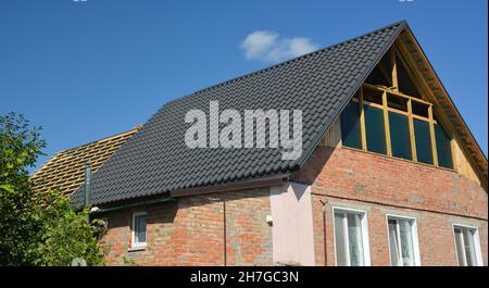 Dachkonstruktion. Eine Ziegelhausrenovierung mit einer Giebel-Dachreparatur auf der Bühne der Dachkonstruktion, Metalldachziegel und Dachfenster Installation. Stockfoto