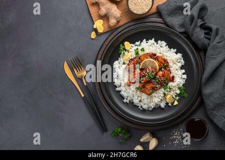 Teriyaki-Huhn mit Reis und Sesam auf dunklem Grund. Stockfoto