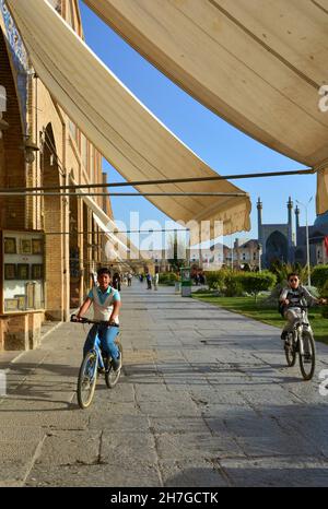 IRAN. ISPAHAN ESFAHAN. KINDER REITEN FAHRRAD AUF DEM EMAM-PLATZ, DER SEIT 1979 ZUM WELTKULTURERBE DER UNESCO GEHÖRT. ERBAUT IM JAHR 1612, IST ES 500M LANG UND 162 Stockfoto