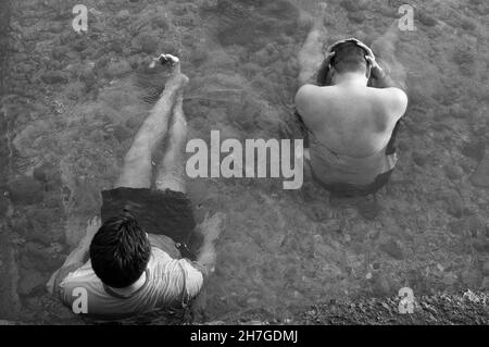 QC, PHILIPPINEN - 01. Jun 2013: Eine Graustufenaufnahme von zwei Freunden am Strand von Batangas auf den Philippinen Stockfoto