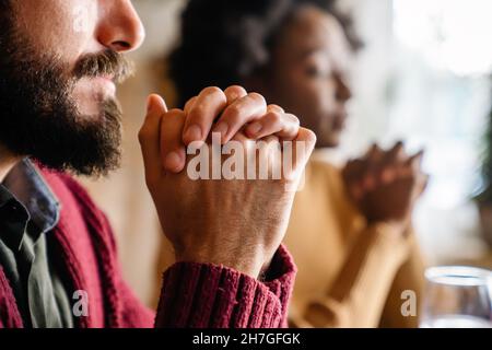 Junge, multiethnische Paare beten zum Herrn, um ihr Essen und ihren Tag zu segnen Stockfoto