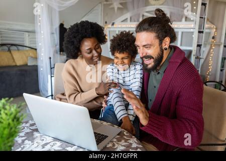 Junge multiethnische fröhliche Familie im Videochat mit Verwandten Stockfoto