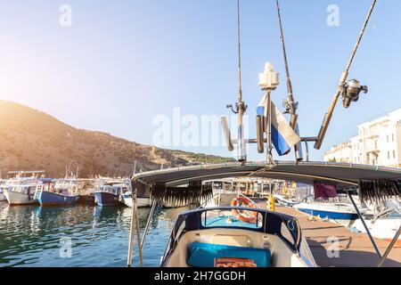 Nahaufnahme von vielen Angelruten und Trocknen von Fischen unter dem Dach eines kleinen Schiffes, das an einem sonnigen Tag in der Marina Bay des Fischerdorfes festgemacht ist. Meer Stockfoto