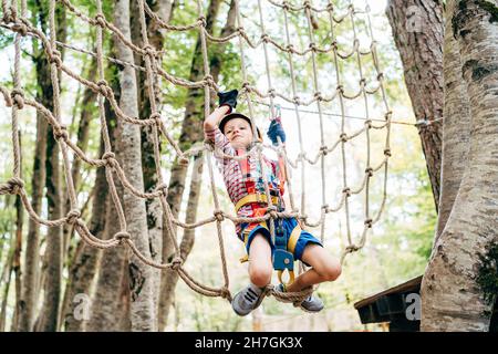 Junge klettert auf einem Gladiatorennetz in einem Abenteuerpark Stockfoto