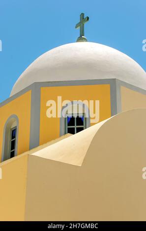 Nahaufnahme eines der typischen gelben Kirchengebäude mit Kuppeldach auf Santorini, Griechenland, vor blauem Himmel Stockfoto