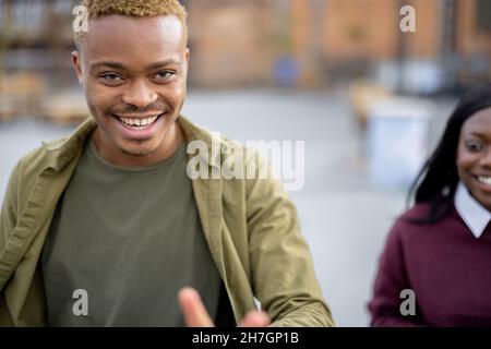 Porträt eines jungen lächelnden hispanischen Mannes, der Spaß auf dem Universitätscampus hat Stockfoto
