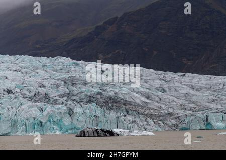 Nahaufnahme der Endstation oder des Gletschers Jokulsarlon, Island, das im Wasser der Lagune endet, mit Bergkette im Hintergrund Stockfoto