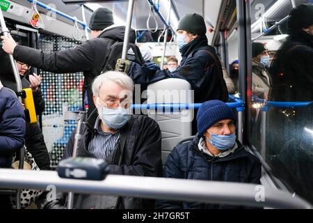 Moskau. Russland. 22. Oktober 2021. Ein älterer grauhaariger Mann mit einer Krücke in einer Gesichtsmaske sitzt auf einem Sitz in einem Stadtbus. Medizinische Masken im öffentlichen Verkehr schützen vor Covid.19 Stockfoto