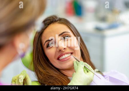 Lächelnde junge Frau am Zahnarztstuhl Stockfoto