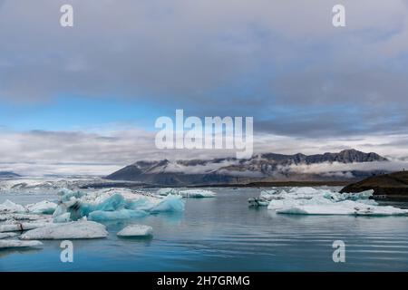 Panoramablick über die Gletscherlagune mit dem Endpunkt oder Ende des Jokulsarlon Gletschers, Island mit verschiedenen blauen arktischen Eisbergen im Vordergrund Stockfoto