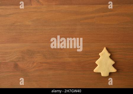 Weihnachtlicher Hintergrund mit tannenförmigem Keks in einer Ecke auf Holzhintergrund. Draufsicht. Horizontale Zusammensetzung. Stockfoto