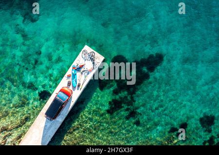 Roadtrip Kroatien, zwei Personen mit Freizeitausrüstung, Fahrrädern, SUP-Board und Camper auf einem Steg Stockfoto