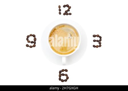 Espressotasse auf einer Untertasse und geröstete Kaffeebohnen als Ziffernblatt auf weißem Hintergrund anordnen. Konzept der Kaffeestzeit. Stockfoto