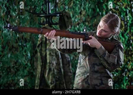 In der Kaserne mißt eine Soldatin mit einem sich selbst wiederholenden Gewehr. Stockfoto