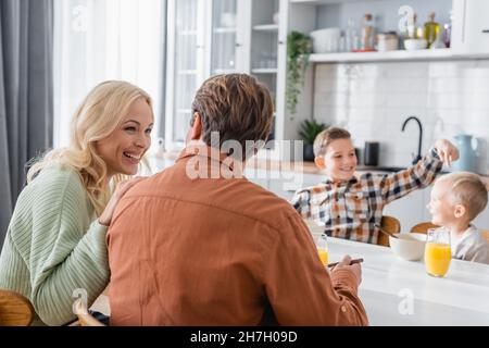 Verschwommener Junge, der Bruder anmalte, während er mit den Eltern in der Küche frühstückte Stockfoto