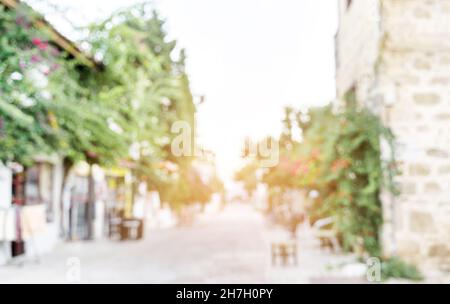 Verschwommener unscharfer Hintergrund einer leeren Spazierstraße in der alten europäischen Stadt, die von untergehenden Sonnenstrahlen beleuchtet ist. Hintergrund für dekorative Werbung. Speicherplatz kopieren. Stockfoto