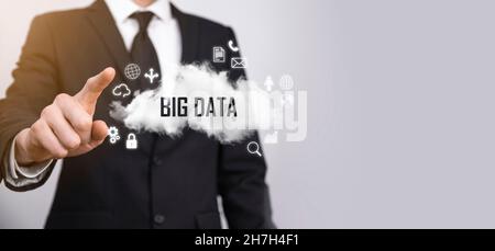 Geschäftsmann hält die Inschrift , Wort BIG DATA . Vorhängeschloss, Gehirn, Mann, Planet, Graph, Lupe, Zahnräder, Symbol für Cloud, Grid, Dokument, Brief, Telefon Stockfoto