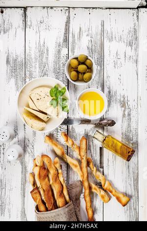 Knusprige Grissini-Brotstäbchen. Traditionelles italienisches Weizenbrot mit Knoblauch, Käse und Sesam. Essen Stillleben auf einem weißen rustikalen Hintergrund. Oliv Stockfoto