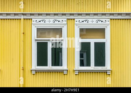 Fenster auf einer gelb gestrichenen Wand, buntes Haus, Architekturdetails in Reykjavik, Island Stockfoto