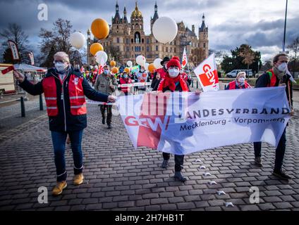 Schwerin, Deutschland. 23rd. November 2021. Lehrer und Mitarbeiter des öffentlichen Dienstes aus Mecklenburg-Vorpommern marschieren zu einer zentralen Kundgebung vor dem Schweriner Schloss. Rund 400 Lehrer, Universitätsangestellte, Polizisten oder Feuerwehrleute nehmen an dem zentralen Ereignis des Warnstreiks Teil. Die Aktion soll den Druck auf die Arbeitgeber bei den Tarifverhandlungen des öffentlichen Dienstes erhöhen. Quelle: Jens Büttner/dpa-Zentralbild/dpa/Alamy Live News Stockfoto